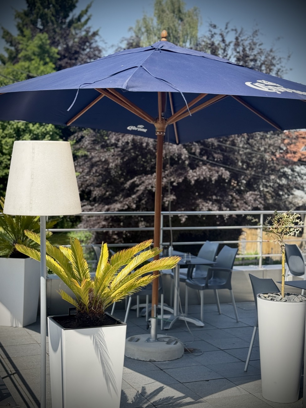 Terrasse verdoyante et parasols du restaurant Le Midi à Verviers